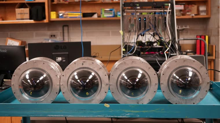 Four large round cylinder like objects on a blue table.
